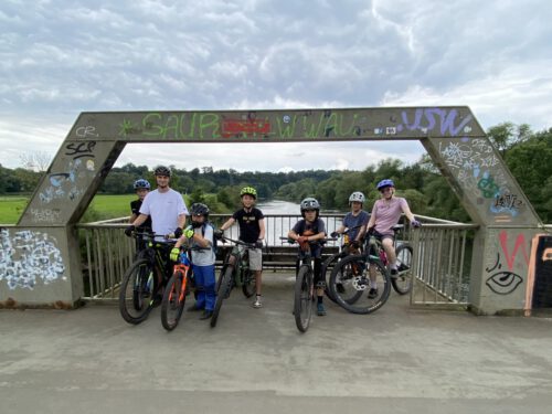 Kinder mit Mountainbikes stehen auf einer Brücke