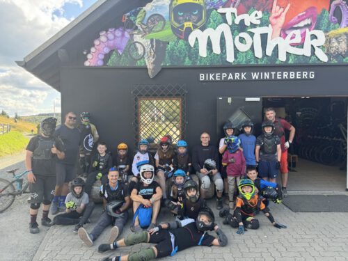 Kinder und Jugendliche auf einem Gruppenbild vor dem Eingang zum Bikepark Winterberg.