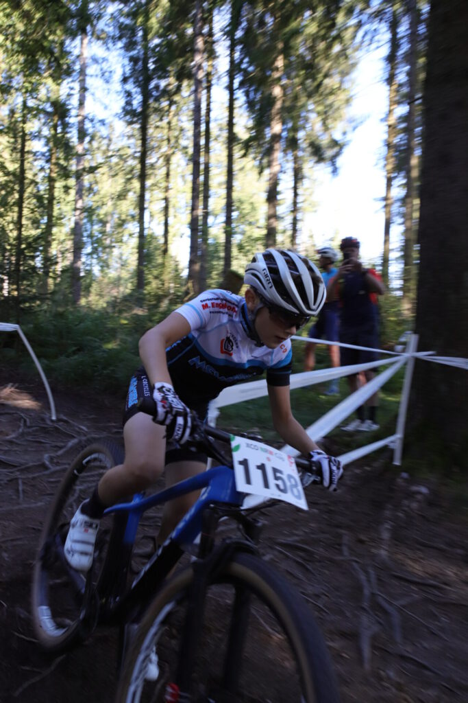 Ein jungedlicher MTB Fahrer fährt in einem Rennen eine wurzelige Strecke hinunter.