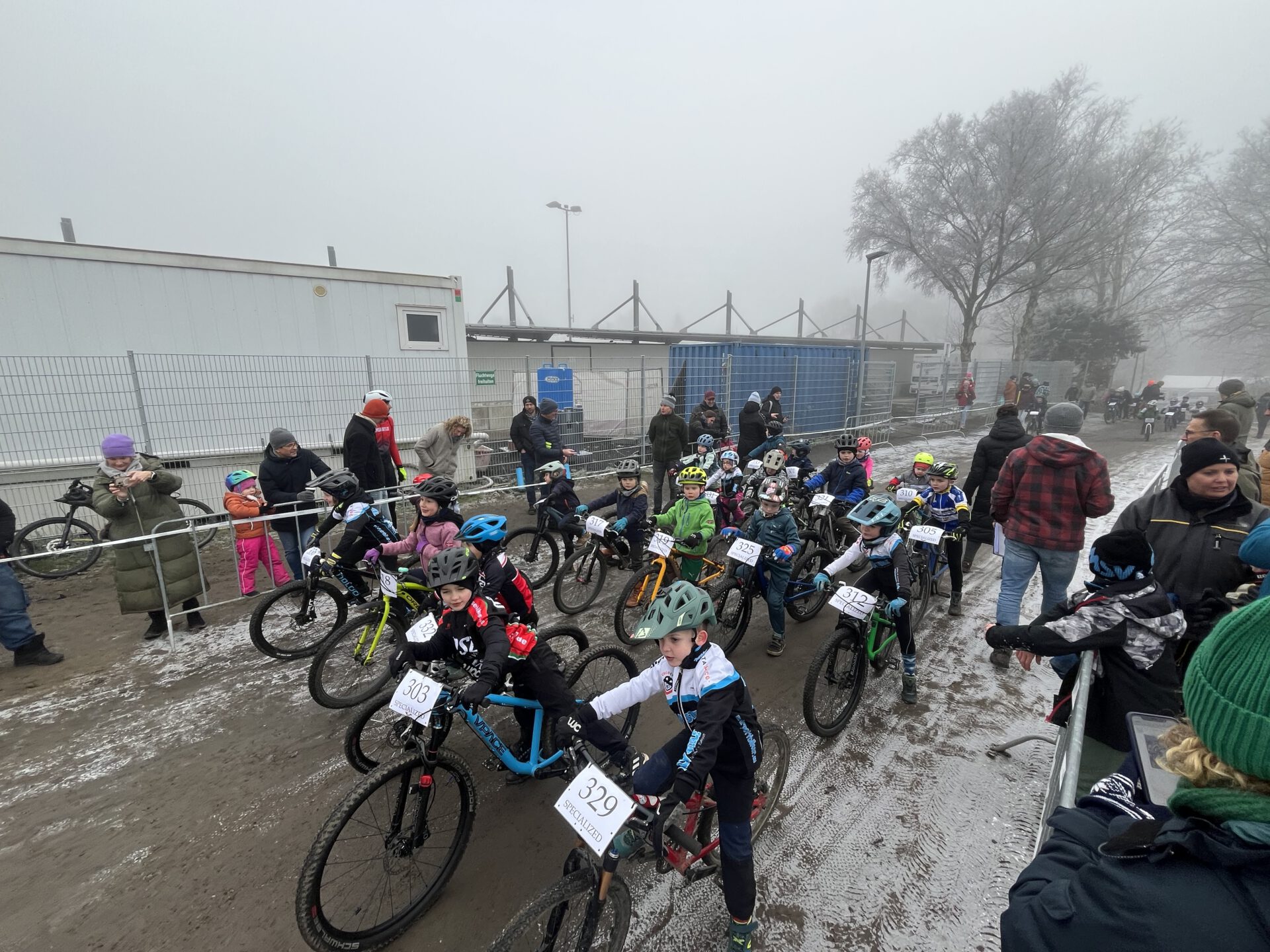 Kinder stehen am Start eines MTB Rennens in winterlicher Landschaft.