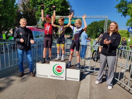 Kinder in Radkleidung jubeln auf einem Podest bei der Siegerehrung.