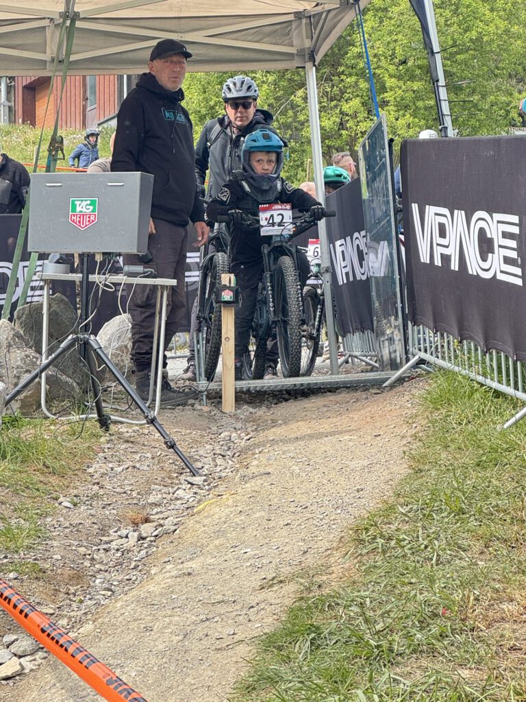 Ein jugendlicher Mountainbikefahrer steht am Start einer Downhillstrecke.