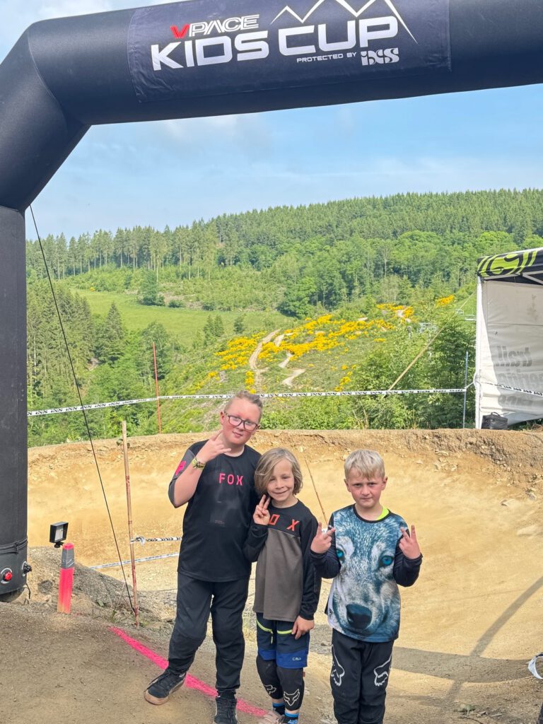 Kinder posieren auf einer Mountainbikestrecke.