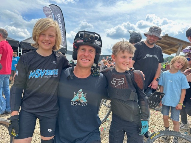 Kinder posieren mit einem Mountainbikefahrer.