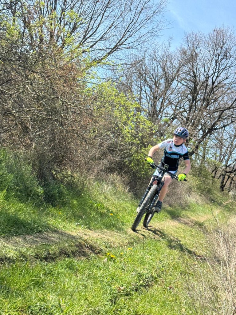 Ein junger Mountainbiker fährt mit Schwung auf einem schmalen Pfad durch die Toskana während des Trainingslagers.