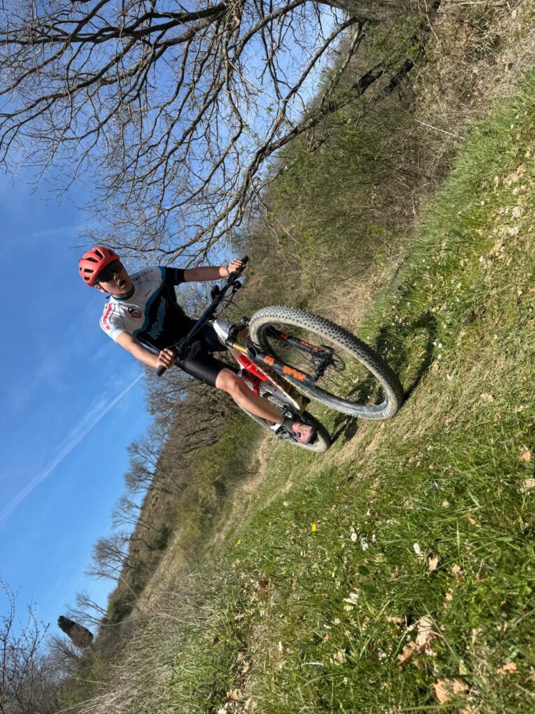 Ein Mountainbiker fährt kraftvoll durch die frühlingshafte Landschaft während des Trainingslagers in der Toskana.