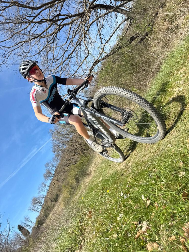 Ein junger Mountainbiker fährt energisch auf einem sonnigen Pfad während des Trainingslagers in der Toskana.