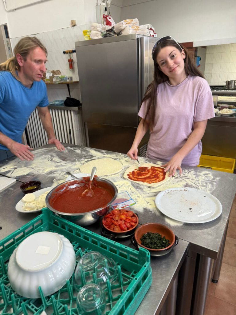 Im Trainingslager in der Toskana bereiten die Teilnehmer gemeinsam Pizzen mit frischen Zutaten vor. | © Name
