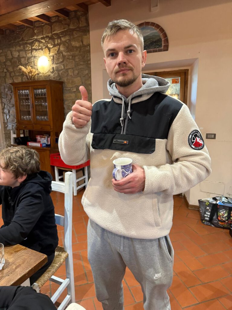 Ein Teilnehmer des Trainingslagers in der Toskana zeigt ein Daumen-hoch-Signal, während er einen Becher hält.